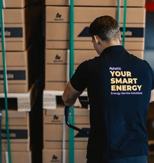 Medewerker van AlphaESS verplaatst pallets met batterijmodules in een magazijn