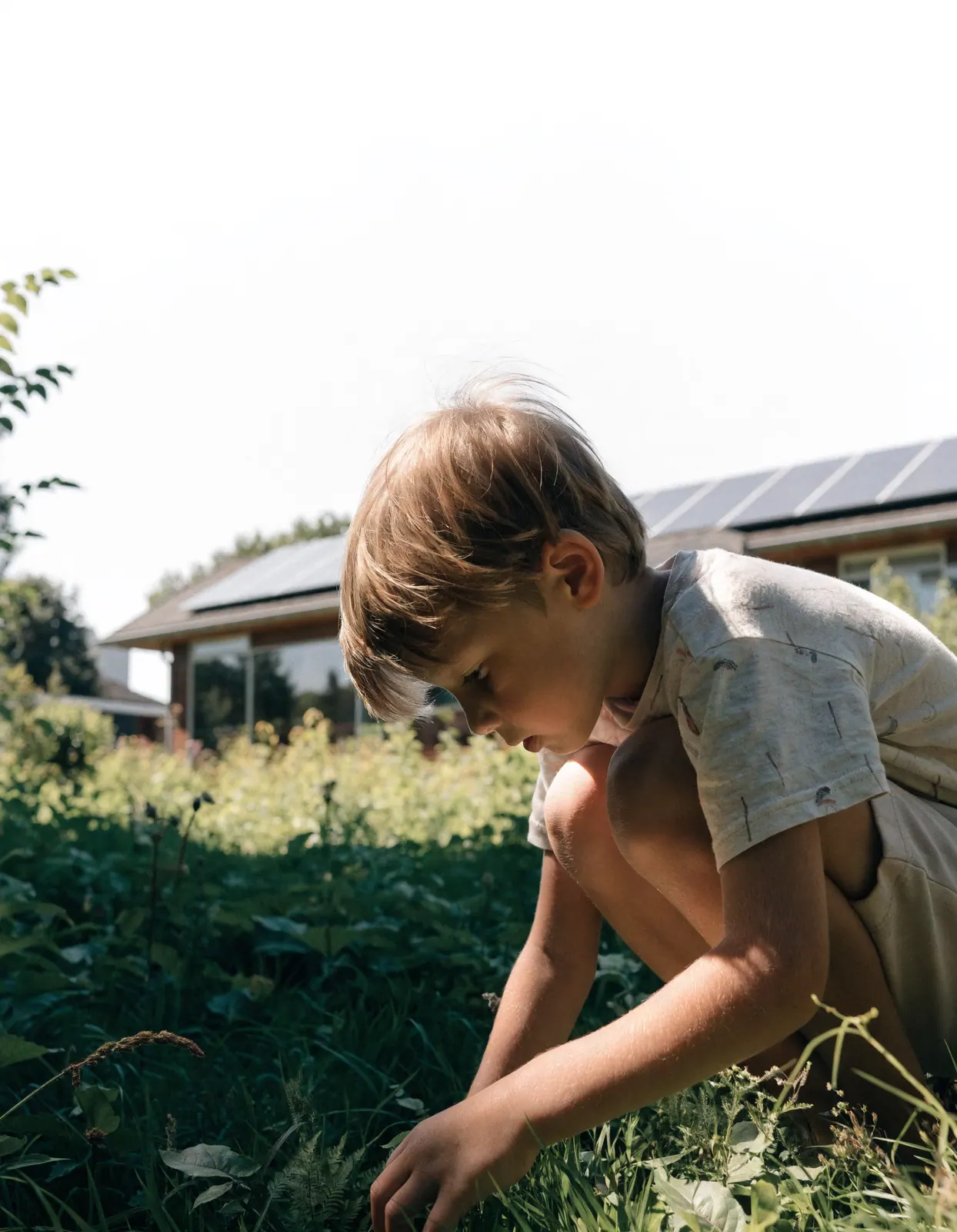 Kind in de tuin bij een woning met zonnepanelen op het dak